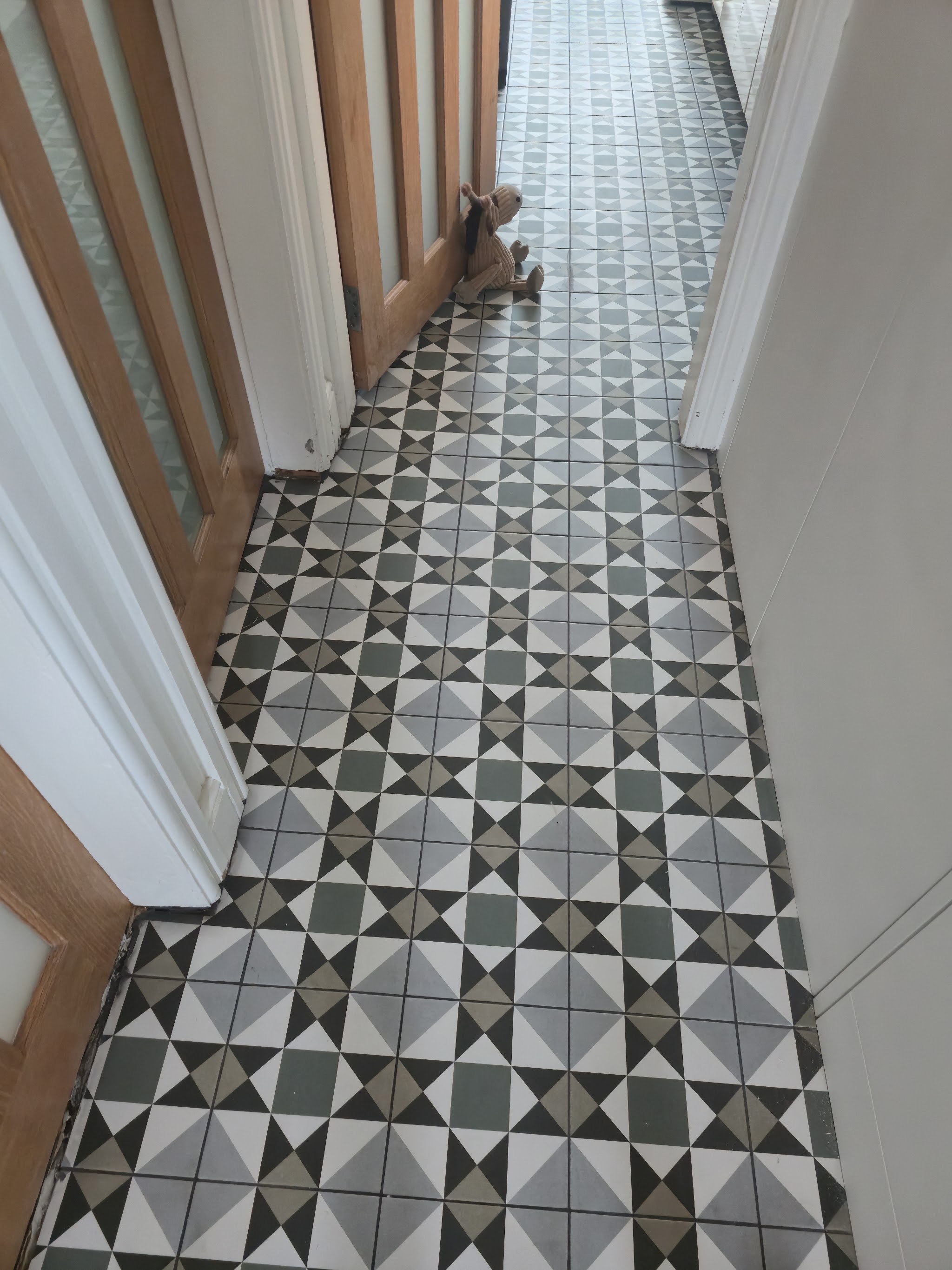 Geometric patterned tile floor running down a hallway between oak doors