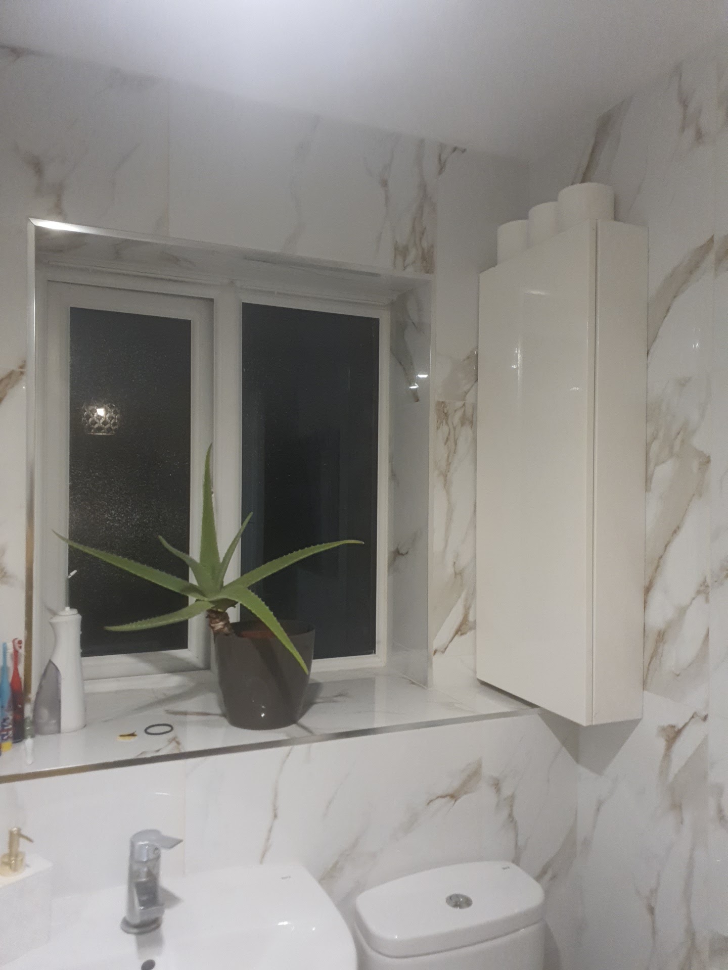 Marble-effect tiled bathroom with a tiled window reveal and sill