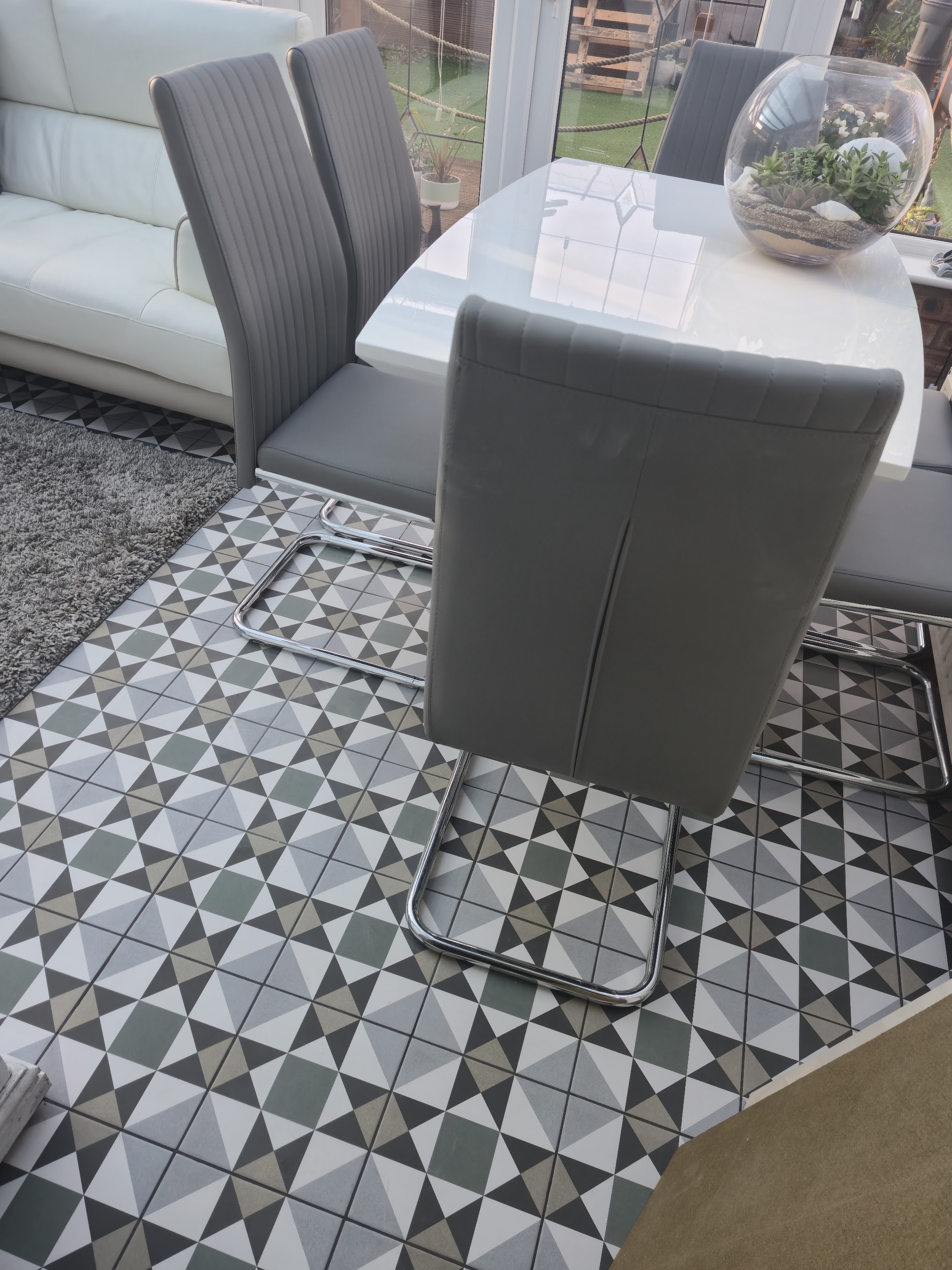 Geometric patterned tile floor in a conservatory beneath a dining table and chairs